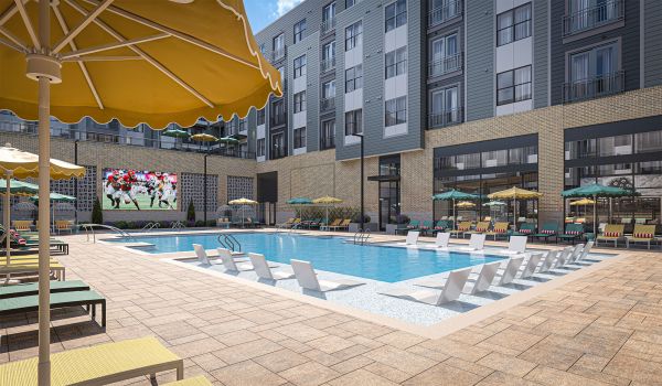 Magnolia Modern apartment pool area with lounge chairs, yellow umbrellas, and a large TV screen showing a football game.